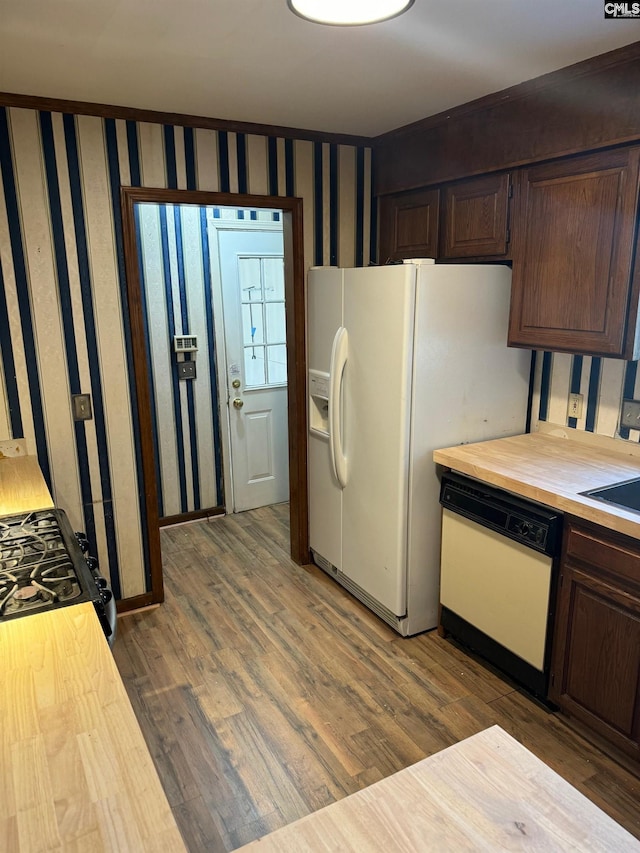 kitchen featuring light wood-type flooring, dark brown cabinets, wood counters, and white appliances