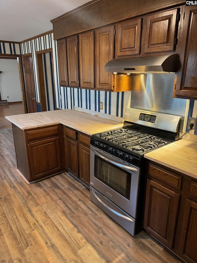 kitchen with ventilation hood, kitchen peninsula, gas range, and wood-type flooring