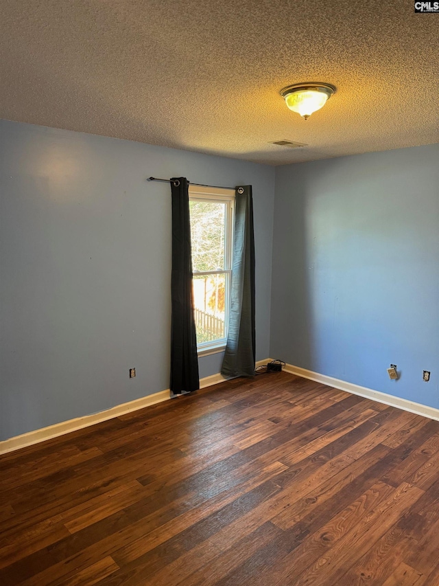 unfurnished room featuring a textured ceiling and dark wood-type flooring