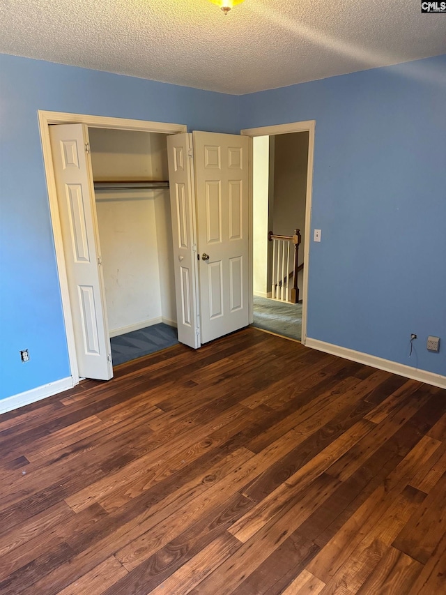 unfurnished bedroom featuring a closet, dark hardwood / wood-style flooring, and a textured ceiling