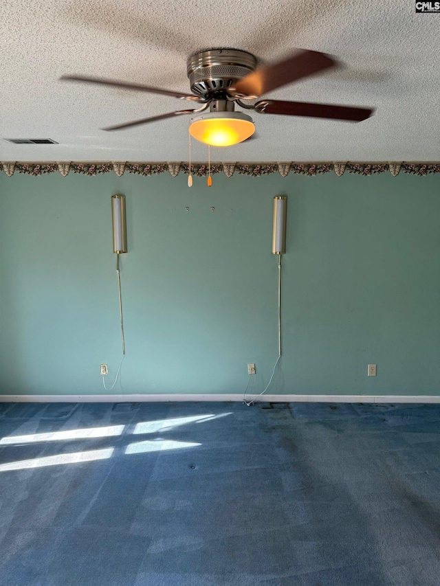 empty room with carpet floors, ceiling fan, and a textured ceiling