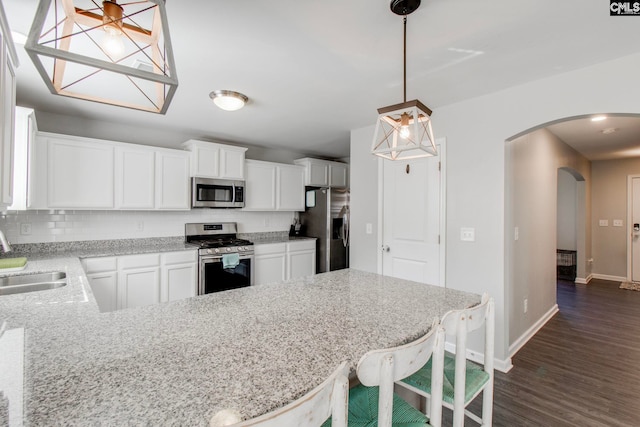 kitchen featuring pendant lighting, sink, appliances with stainless steel finishes, a kitchen breakfast bar, and white cabinets