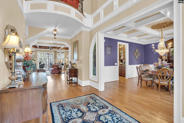 entrance foyer with ceiling fan with notable chandelier, beamed ceiling, hardwood / wood-style flooring, crown molding, and coffered ceiling