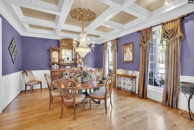 dining space with beam ceiling, coffered ceiling, light wood-type flooring, ornamental molding, and a chandelier