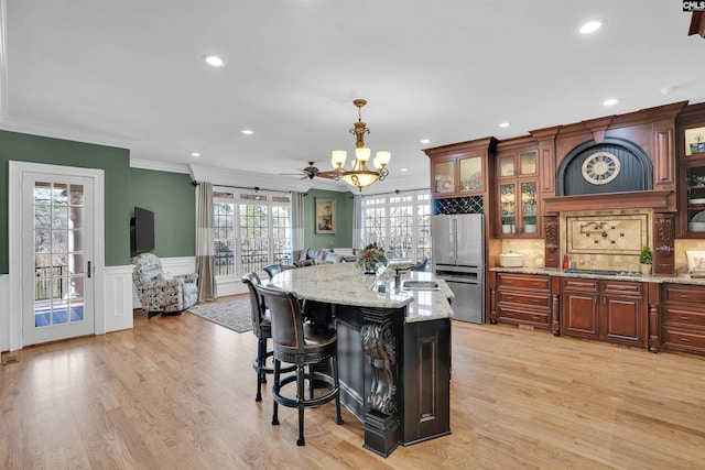 kitchen with a kitchen island, decorative light fixtures, stainless steel appliances, light stone counters, and crown molding