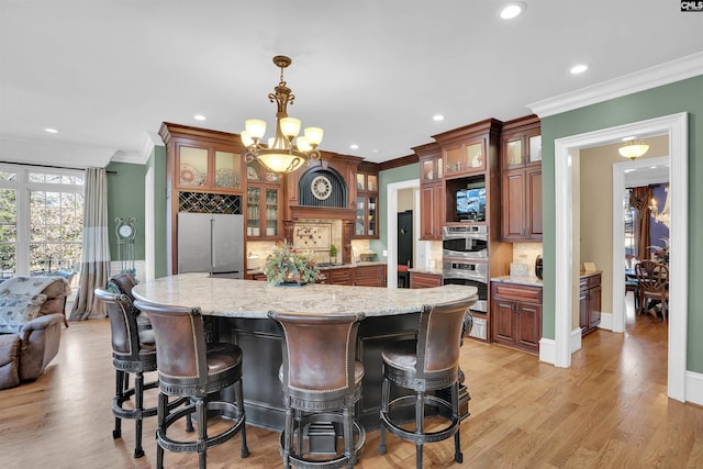 kitchen with pendant lighting, appliances with stainless steel finishes, a center island, light hardwood / wood-style floors, and ornamental molding