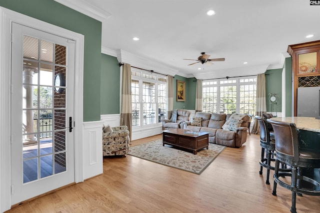 living room with ceiling fan, ornamental molding, and light wood-type flooring