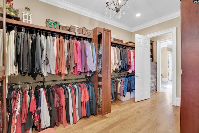 spacious closet with a chandelier and light hardwood / wood-style flooring