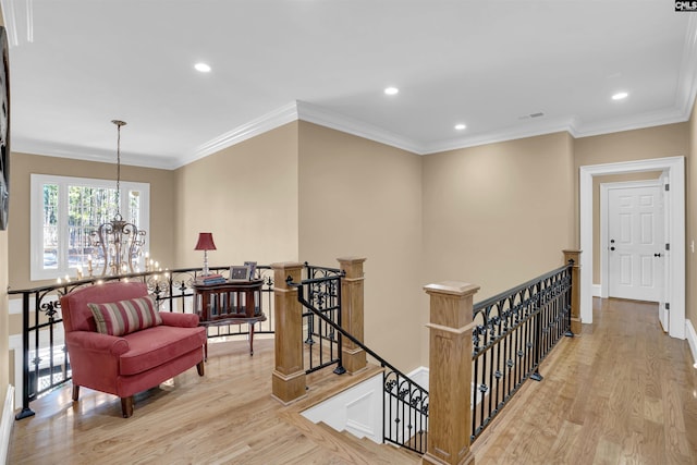 hallway featuring a notable chandelier, ornamental molding, and light hardwood / wood-style flooring