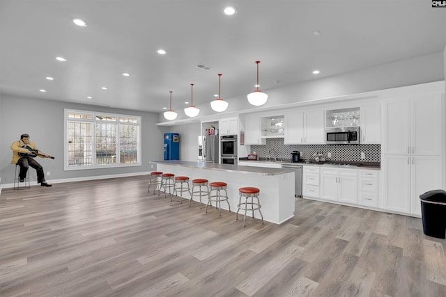 kitchen featuring pendant lighting, white cabinets, appliances with stainless steel finishes, a center island, and tasteful backsplash