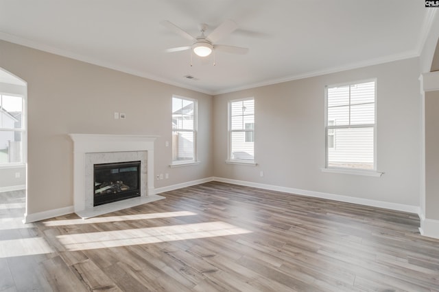 unfurnished living room featuring light wood finished floors, baseboards, a ceiling fan, ornamental molding, and a fireplace