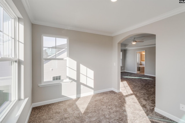 carpeted spare room featuring arched walkways, ornamental molding, and baseboards