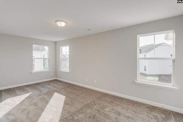 unfurnished room featuring carpet floors, visible vents, and baseboards