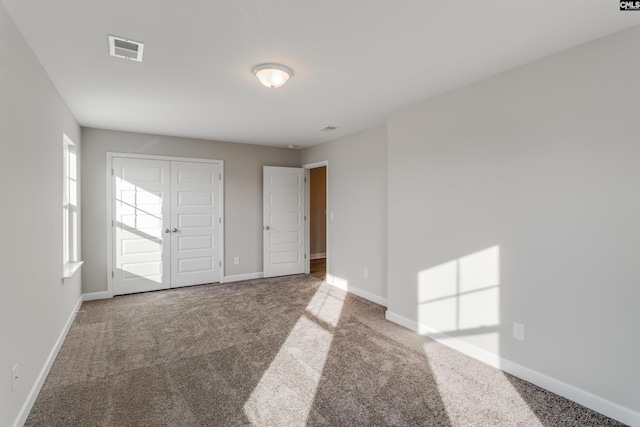 carpeted spare room featuring baseboards and visible vents