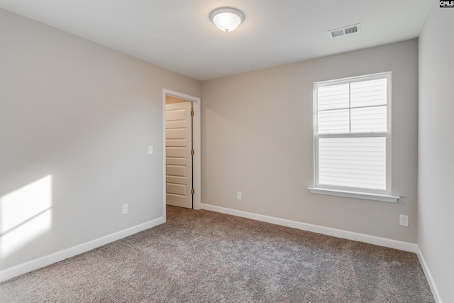 carpeted spare room with visible vents and baseboards