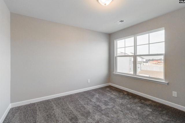 unfurnished room featuring baseboards, visible vents, and dark colored carpet