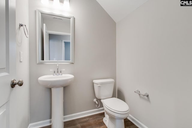 bathroom featuring hardwood / wood-style flooring, sink, toilet, and vaulted ceiling