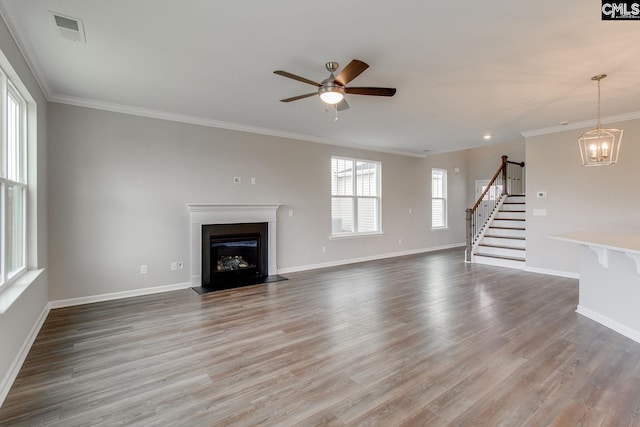 unfurnished living room featuring ceiling fan with notable chandelier, wood-type flooring, and ornamental molding