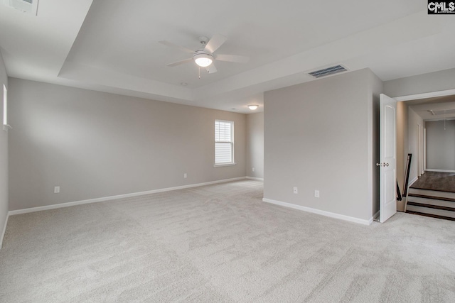 spare room with light carpet, ceiling fan, and a tray ceiling