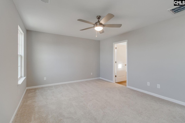 spare room with baseboards, visible vents, a ceiling fan, carpet flooring, and a wealth of natural light