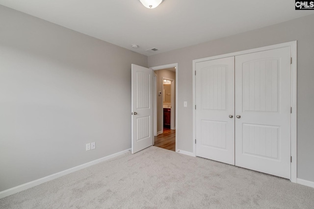 unfurnished bedroom featuring carpet floors, visible vents, baseboards, and a closet