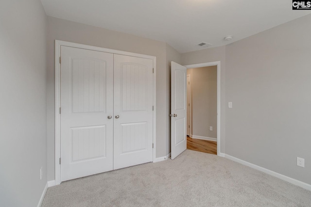 unfurnished bedroom featuring carpet floors, a closet, visible vents, and baseboards