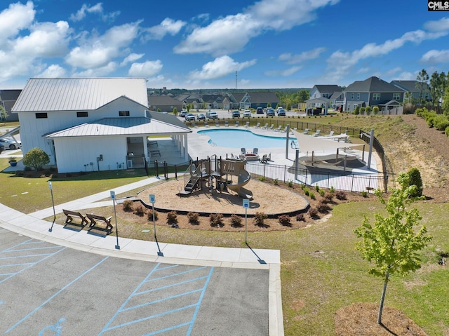 view of home's community with uncovered parking, a residential view, playground community, and fence