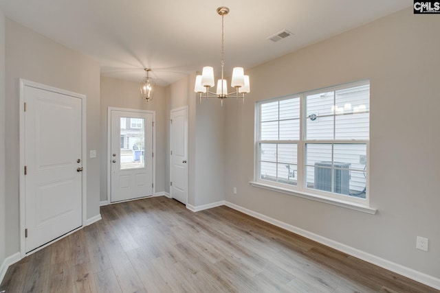 foyer featuring baseboards, visible vents, a notable chandelier, and wood finished floors