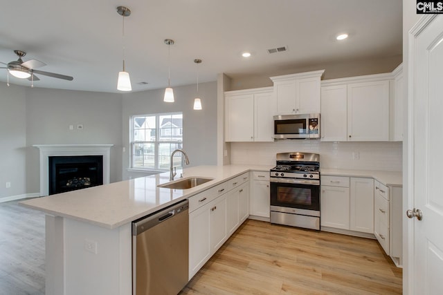 kitchen with stainless steel appliances, tasteful backsplash, visible vents, a sink, and a peninsula