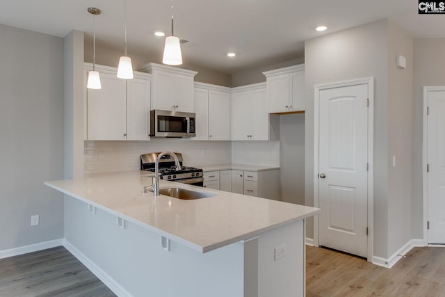 kitchen featuring a peninsula, light wood-style flooring, stainless steel appliances, and decorative backsplash