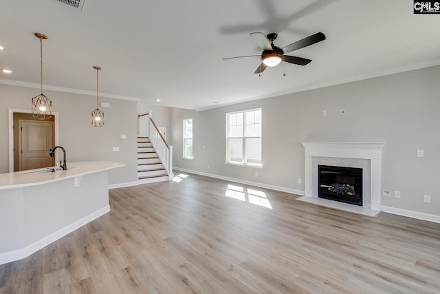 unfurnished living room with light wood finished floors, stairs, baseboards, and a sink