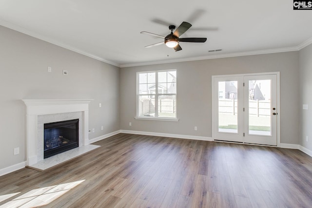 unfurnished living room featuring a high end fireplace, a wealth of natural light, visible vents, and dark wood finished floors