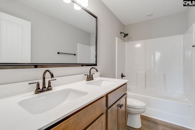 bathroom with shower / bathtub combination, double vanity, a sink, and toilet