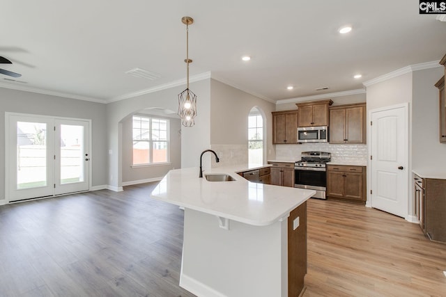 kitchen with visible vents, appliances with stainless steel finishes, a peninsula, light wood-type flooring, and a sink