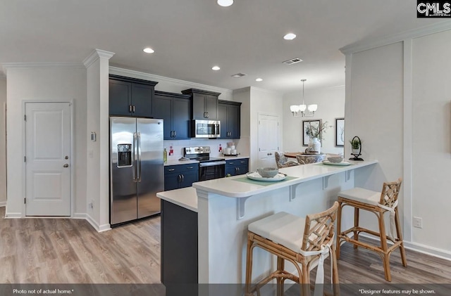 kitchen with visible vents, a peninsula, stainless steel appliances, light countertops, and a kitchen bar