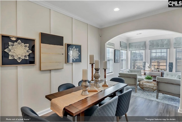 dining space featuring arched walkways, crown molding, recessed lighting, and wood finished floors