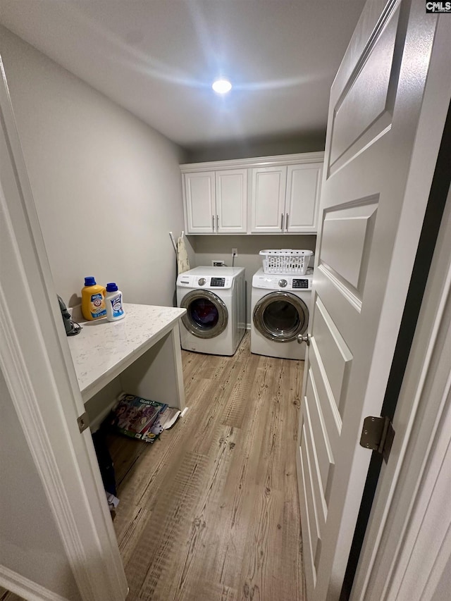 washroom with washing machine and clothes dryer, light hardwood / wood-style floors, and cabinets