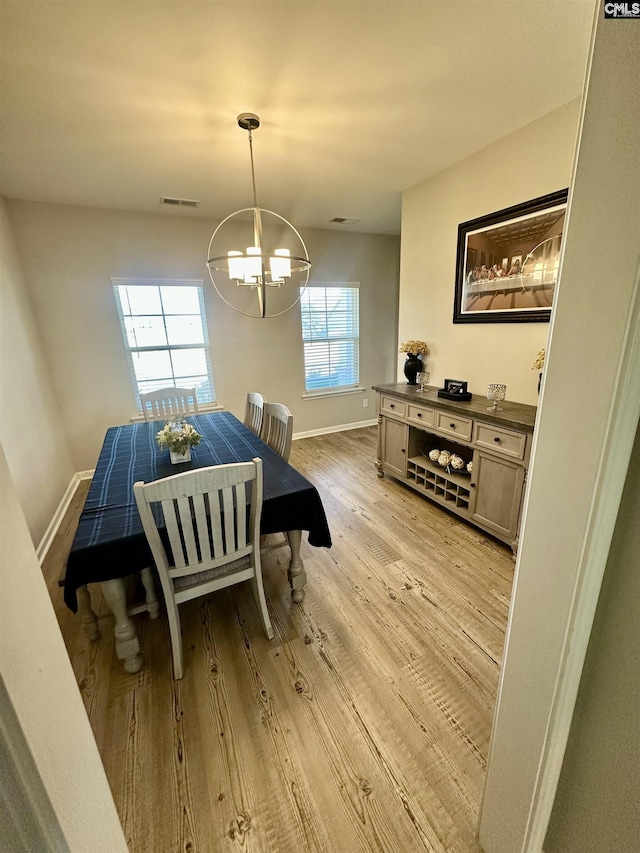 dining area with light hardwood / wood-style flooring and a notable chandelier