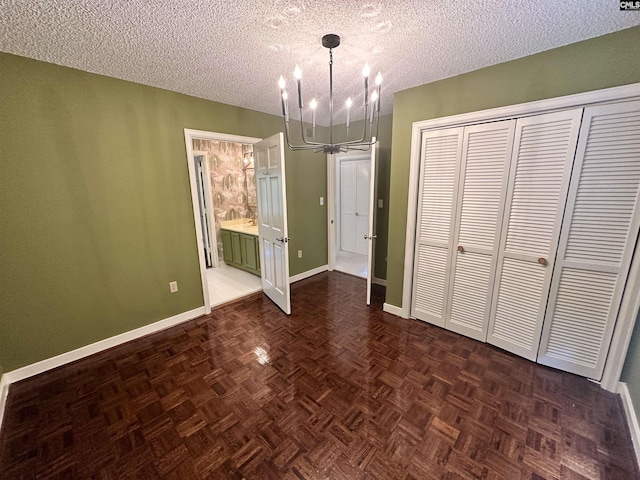 unfurnished bedroom with dark parquet flooring, a textured ceiling, a chandelier, and a closet