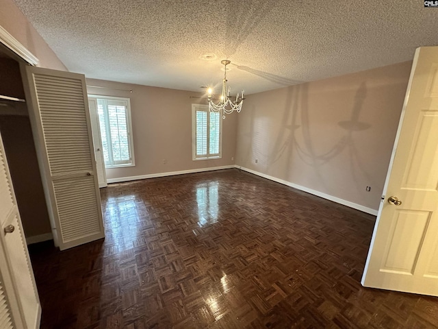 interior space featuring dark parquet floors, a textured ceiling, and a notable chandelier