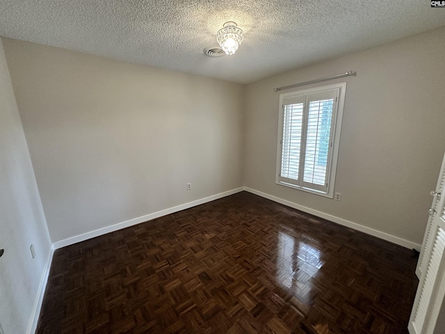 empty room with a textured ceiling and dark parquet floors