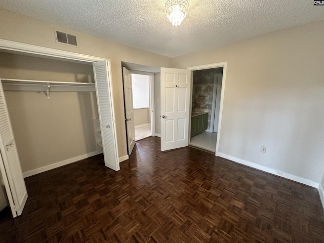 unfurnished bedroom with dark parquet flooring, a closet, and a textured ceiling