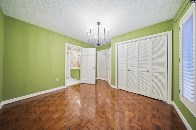 unfurnished bedroom featuring dark parquet flooring, a textured ceiling, an inviting chandelier, and a closet