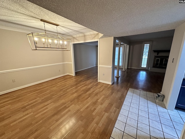 unfurnished dining area featuring hardwood / wood-style flooring, ornamental molding, a textured ceiling, and a chandelier