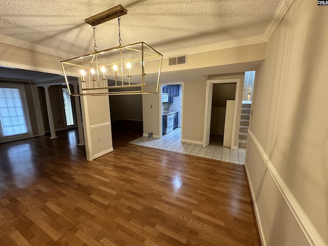 interior space featuring crown molding, wood-type flooring, decorative columns, and a textured ceiling