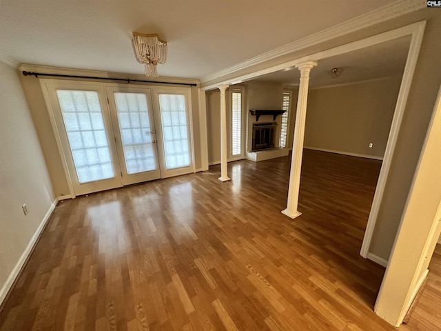 empty room with crown molding, wood-type flooring, french doors, and ornate columns