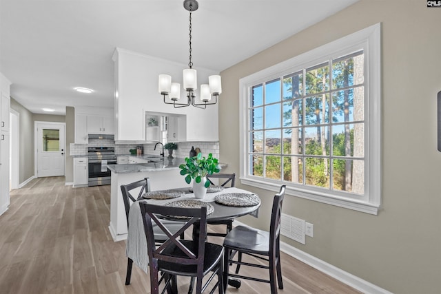 dining space with a notable chandelier, light hardwood / wood-style flooring, and sink