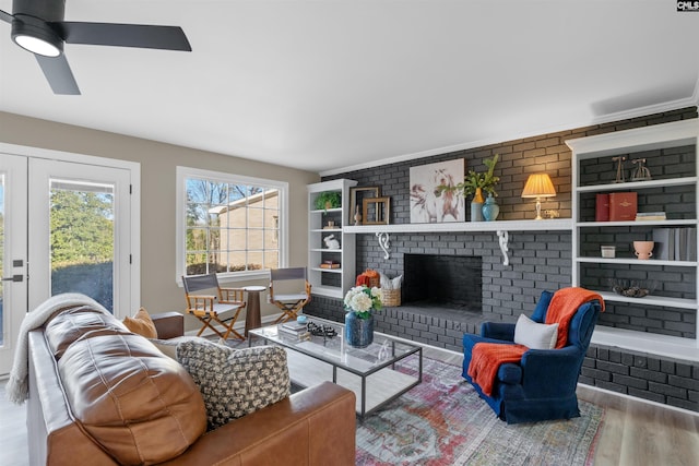 living room featuring a brick fireplace, brick wall, wood-type flooring, and ceiling fan