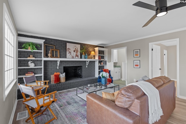 living room with a wealth of natural light, crown molding, a fireplace, and hardwood / wood-style flooring