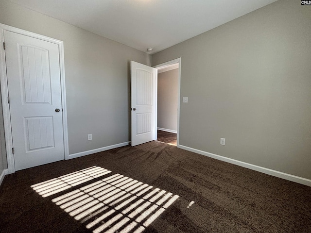 unfurnished bedroom featuring a closet and dark carpet